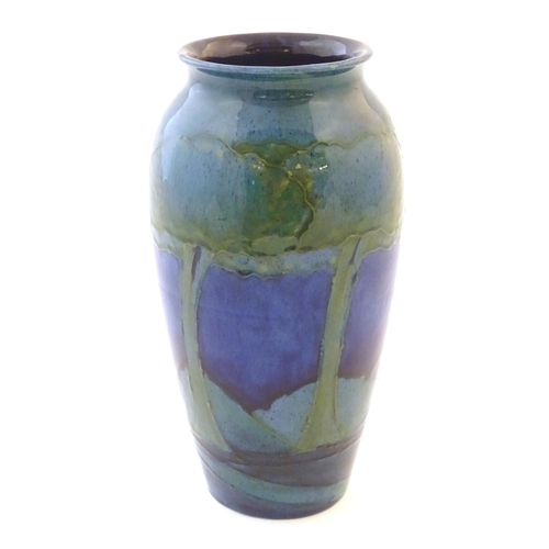 116 - An Art Nouveau Moorcroft vase in the pattern Moonlit Blue decorated with trees in a landscape with r... 