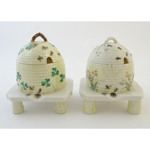 128 - Two Belleek honey / preserve pots and covers formed as bee hives / skeps with bee, shamrock / cover ... 