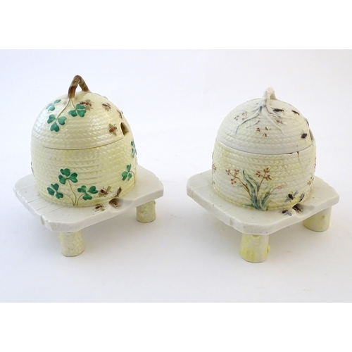 128 - Two Belleek honey / preserve pots and covers formed as bee hives / skeps with bee, shamrock / cover ... 