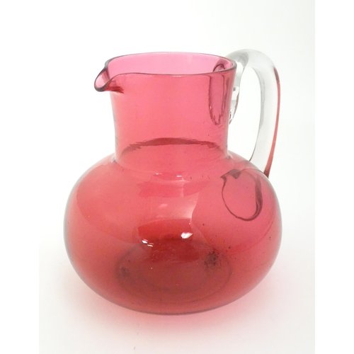 275 - A late 19thC / early 20thC cranberry glass jug with clear glass handle. 6