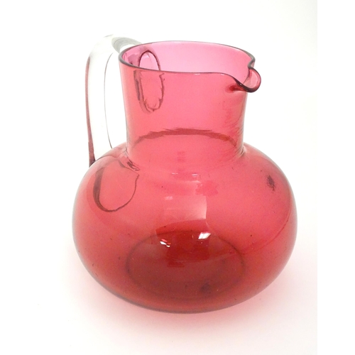 275 - A late 19thC / early 20thC cranberry glass jug with clear glass handle. 6