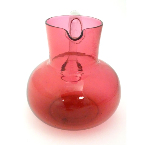 275 - A late 19thC / early 20thC cranberry glass jug with clear glass handle. 6