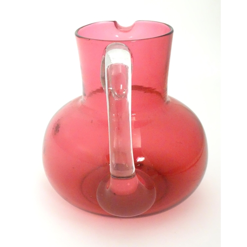 275 - A late 19thC / early 20thC cranberry glass jug with clear glass handle. 6