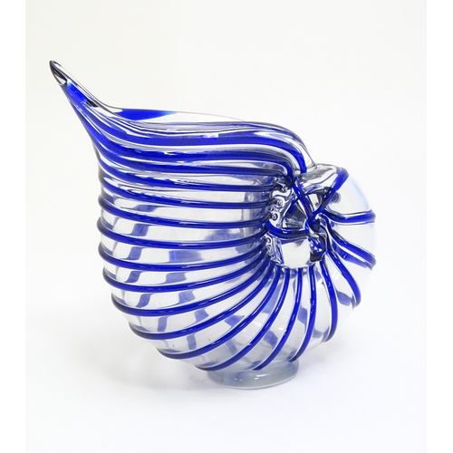 294 - A studio glass jug formed as a stylised nautilus shell, the clear glass body with blue banded detail... 