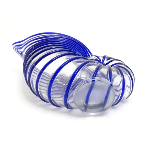 294 - A studio glass jug formed as a stylised nautilus shell, the clear glass body with blue banded detail... 