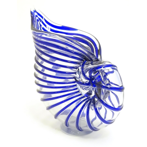 294 - A studio glass jug formed as a stylised nautilus shell, the clear glass body with blue banded detail... 