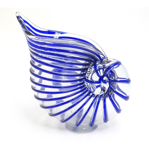 294 - A studio glass jug formed as a stylised nautilus shell, the clear glass body with blue banded detail... 