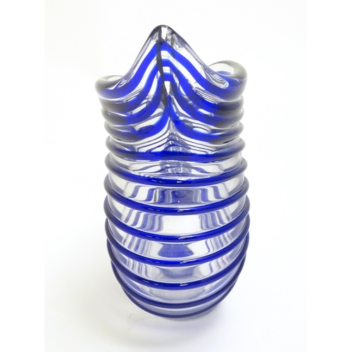 294 - A studio glass jug formed as a stylised nautilus shell, the clear glass body with blue banded detail... 