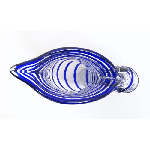 294 - A studio glass jug formed as a stylised nautilus shell, the clear glass body with blue banded detail... 