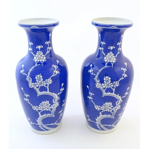 62 - A pair of Oriental vases with a blue glaze decorated with prunus flowers in blossom. Character marke... 