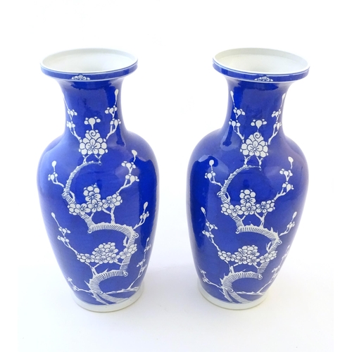 62 - A pair of Oriental vases with a blue glaze decorated with prunus flowers in blossom. Character marke... 