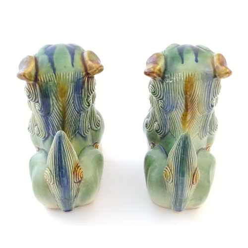 67 - A matched pair of Chinese models of foo dogs / guardian lions with a green, blue and ochre glaze. Ap... 