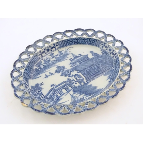 72 - A blue and white dish of oval form with reticulated border decorated with a seascape scene with pago... 