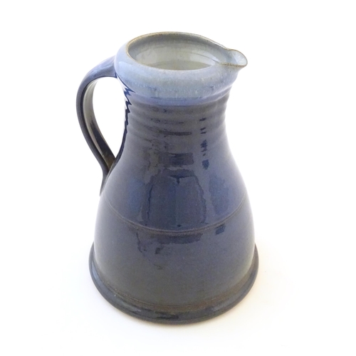 89 - A studio pottery jug with a blue glaze, ribbed neck and banded detail. Impressed mark to under handl... 