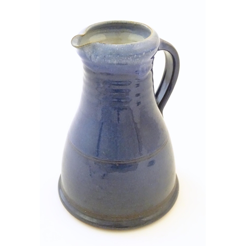 89 - A studio pottery jug with a blue glaze, ribbed neck and banded detail. Impressed mark to under handl... 