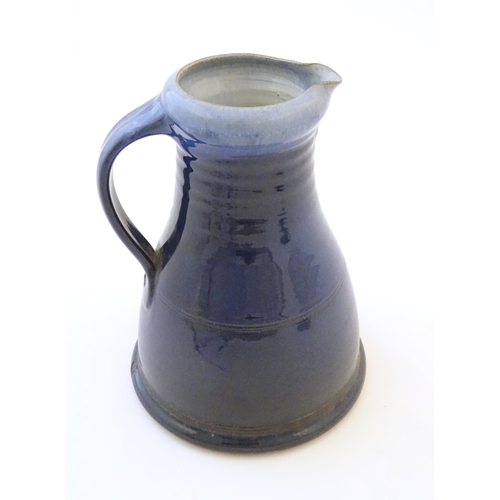 89 - A studio pottery jug with a blue glaze, ribbed neck and banded detail. Impressed mark to under handl... 