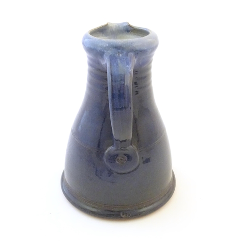 89 - A studio pottery jug with a blue glaze, ribbed neck and banded detail. Impressed mark to under handl... 