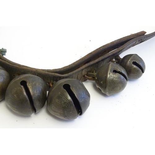 1190 - Agricultural bygones : Twelve late 19th / early 20thC crotal bells / rumble bells mounted on a leath... 