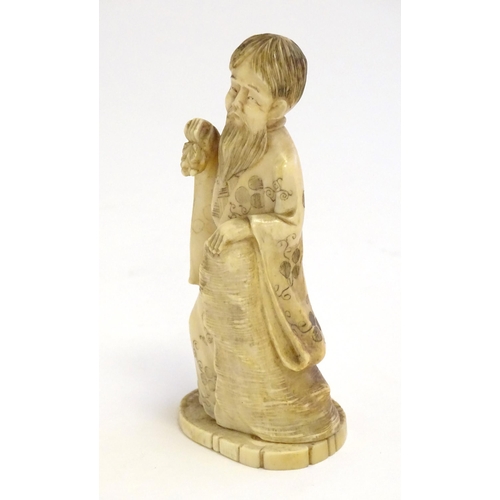 1245 - A 19thC Oriental carved ivory figure depicting a gentleman in robes. Approx. 4 1/2