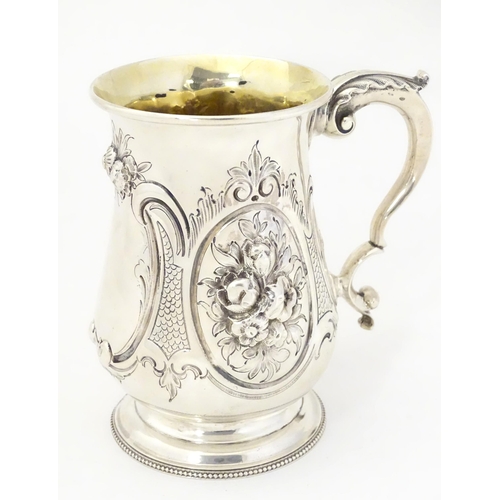 341 - A Victorian silver mug with embossed decoration and gilded interior. Hallmarked London 1864 maker Au... 