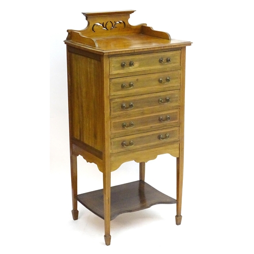 2083 - An early 20thC mahogany music cabinet with a shaped pierced upstand and five drawers with drop ends,... 