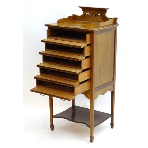 2083 - An early 20thC mahogany music cabinet with a shaped pierced upstand and five drawers with drop ends,... 