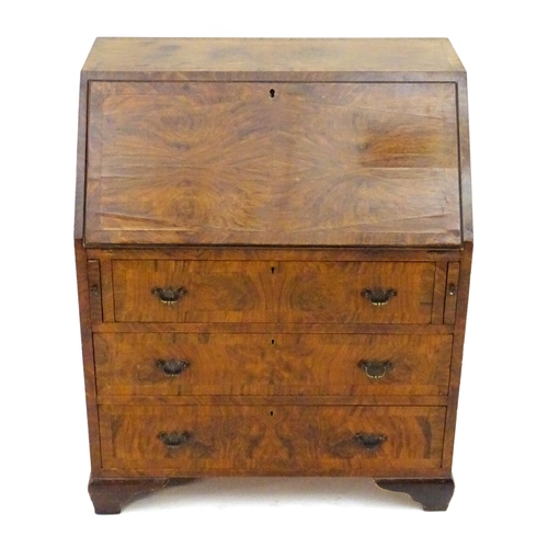 2088 - A late 19thC / early 20thC walnut bureau with a fall front above three long drawers having brass han... 