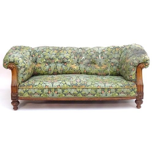 2092 - A Victorian oak framed Chesterfield settee, with scrolled and carved arms above floral detailing and... 