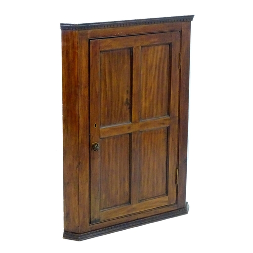 2095 - A late 18thC mahogany corner cupboard with a moulded cornice above a four panelled door and cast met... 