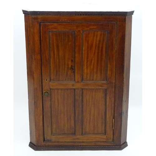 2095 - A late 18thC mahogany corner cupboard with a moulded cornice above a four panelled door and cast met... 