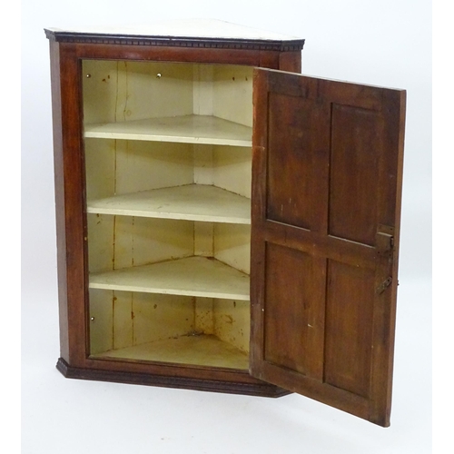 2095 - A late 18thC mahogany corner cupboard with a moulded cornice above a four panelled door and cast met... 