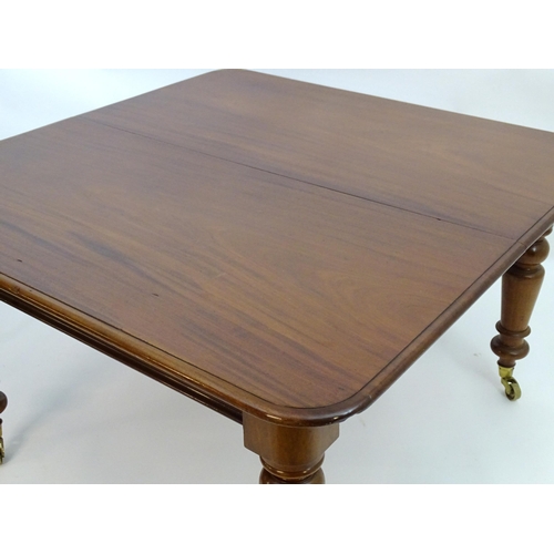 2113 - A late 19thC mahogany dining table with a moulded top above four large turned tapering legs terminat... 