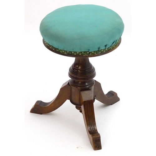 2115 - A late 19thC / early 20thC walnut piano stool with an adjustable upholstered top. 20