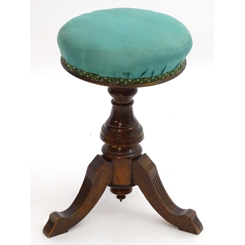 2115 - A late 19thC / early 20thC walnut piano stool with an adjustable upholstered top. 20