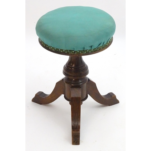 2115 - A late 19thC / early 20thC walnut piano stool with an adjustable upholstered top. 20