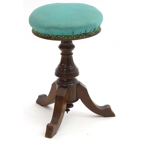 2115 - A late 19thC / early 20thC walnut piano stool with an adjustable upholstered top. 20