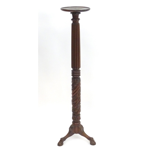 2117 - A late 19thC / early 20thC mahogany torchiere with a dished top above a reeded and carved stem with ... 