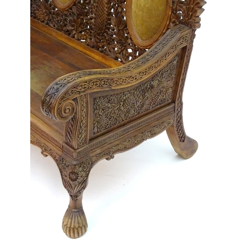 2204 - A carved oriental sofa with pierced decoration and three backrests above swept arms, a panelled seat... 