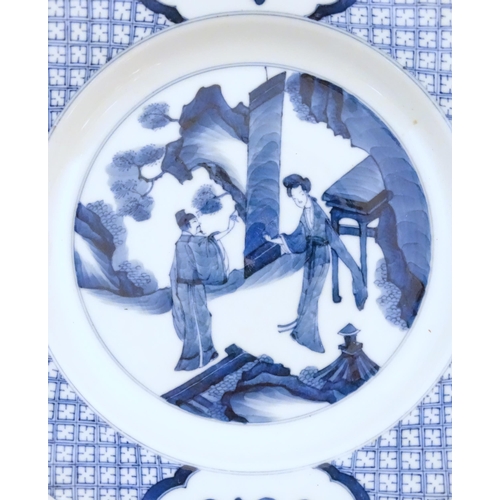 24A - A Chinese blue and white plate decorated with two figures in a landscape scene, the border with ausp... 