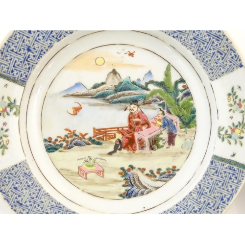 31A - A pair of Chinese plates depicting a two figures in a garden watching a bat, with sea and mountains ... 
