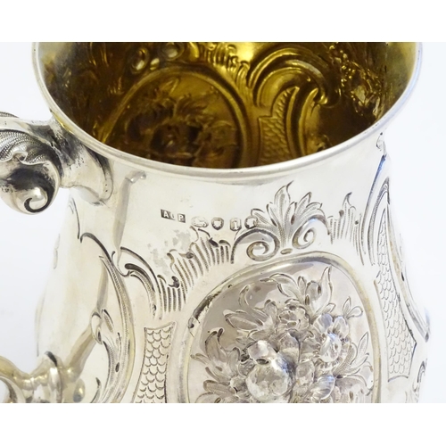 341 - A Victorian silver mug with embossed decoration and gilded interior. Hallmarked London 1864 maker Au... 