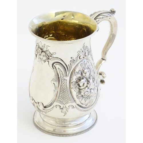 341 - A Victorian silver mug with embossed decoration and gilded interior. Hallmarked London 1864 maker Au... 