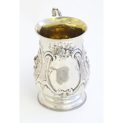 341 - A Victorian silver mug with embossed decoration and gilded interior. Hallmarked London 1864 maker Au... 