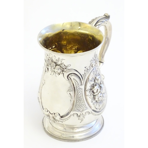 341 - A Victorian silver mug with embossed decoration and gilded interior. Hallmarked London 1864 maker Au... 