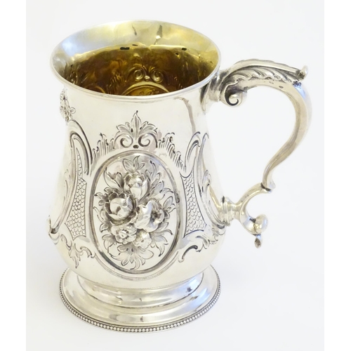 341 - A Victorian silver mug with embossed decoration and gilded interior. Hallmarked London 1864 maker Au... 