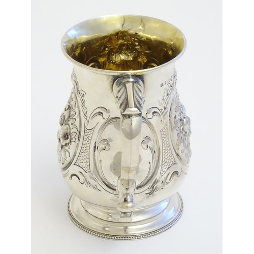 341 - A Victorian silver mug with embossed decoration and gilded interior. Hallmarked London 1864 maker Au... 