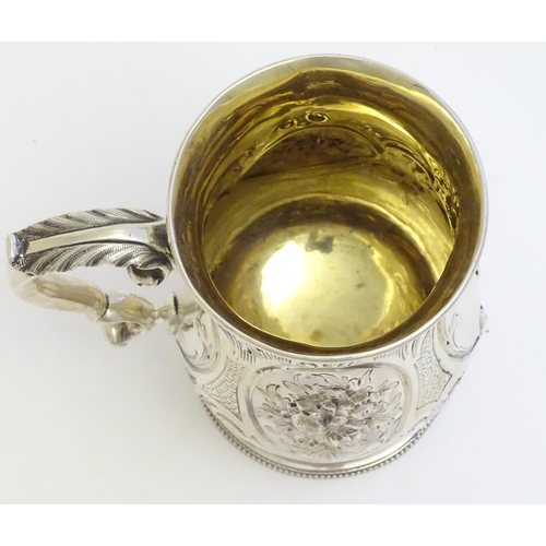 341 - A Victorian silver mug with embossed decoration and gilded interior. Hallmarked London 1864 maker Au... 