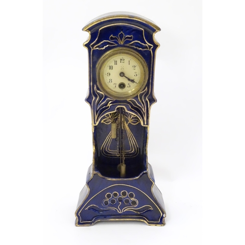 2286 - A Jugendstil mantle clock formed as a ceramic cased long case clock with blue and gilt detail. the d... 