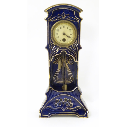 2286 - A Jugendstil mantle clock formed as a ceramic cased long case clock with blue and gilt detail. the d... 