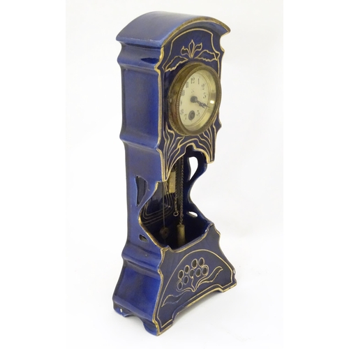 2286 - A Jugendstil mantle clock formed as a ceramic cased long case clock with blue and gilt detail. the d... 